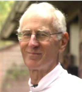 Elderly man smiling outdoors, advocating environmental conservation and protection efforts.